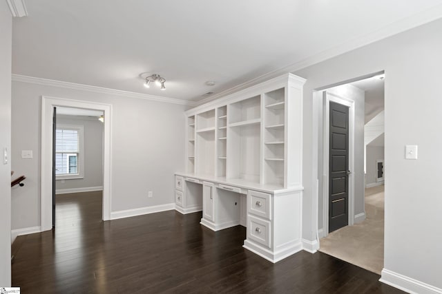 unfurnished office featuring built in study area, dark wood-style floors, baseboards, and crown molding