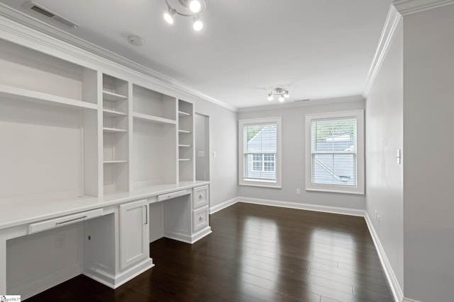 unfurnished office with dark wood-style flooring, baseboards, built in desk, ornamental molding, and visible vents