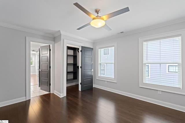 unfurnished bedroom with visible vents, baseboards, crown molding, and wood finished floors