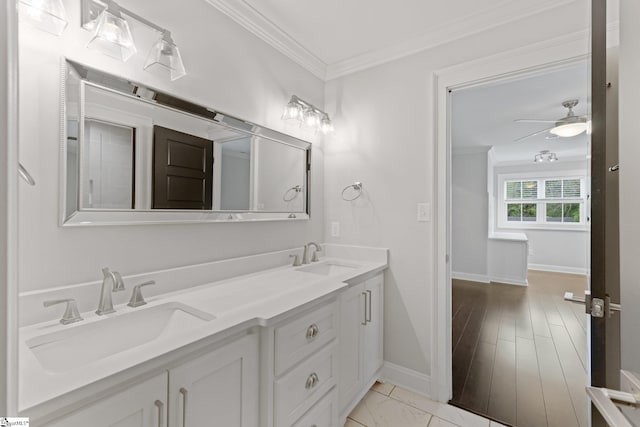 bathroom with crown molding, double vanity, a sink, and baseboards