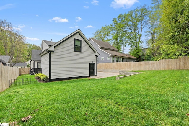 back of house with a fenced backyard and a lawn