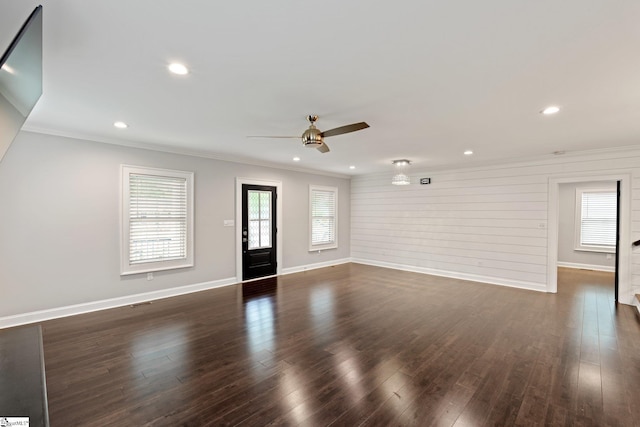 unfurnished living room featuring dark wood-type flooring, crown molding, baseboards, and a ceiling fan