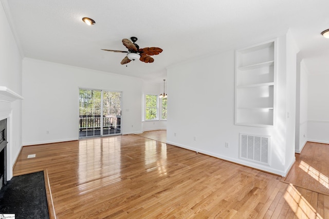 unfurnished living room with ceiling fan with notable chandelier, a fireplace with flush hearth, light wood-style flooring, visible vents, and baseboards