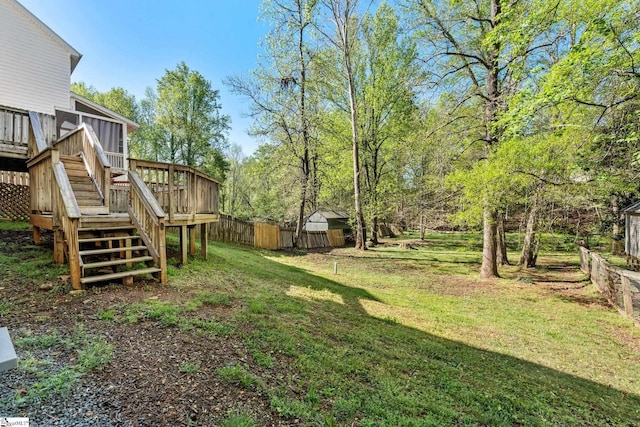 view of yard with an outbuilding, stairway, a storage unit, fence, and a deck