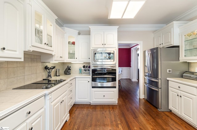 kitchen with glass insert cabinets, dark wood finished floors, crown molding, white cabinetry, and stainless steel appliances