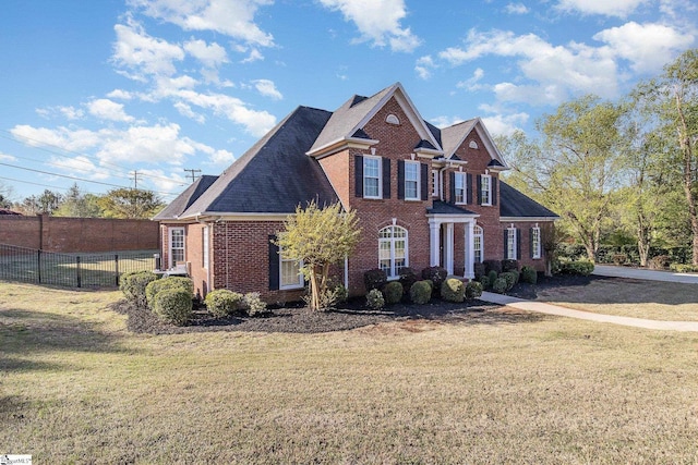 view of front of house with brick siding, fence, and a front lawn