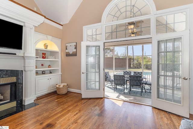 doorway to outside with built in features, baseboards, wood finished floors, and a fireplace