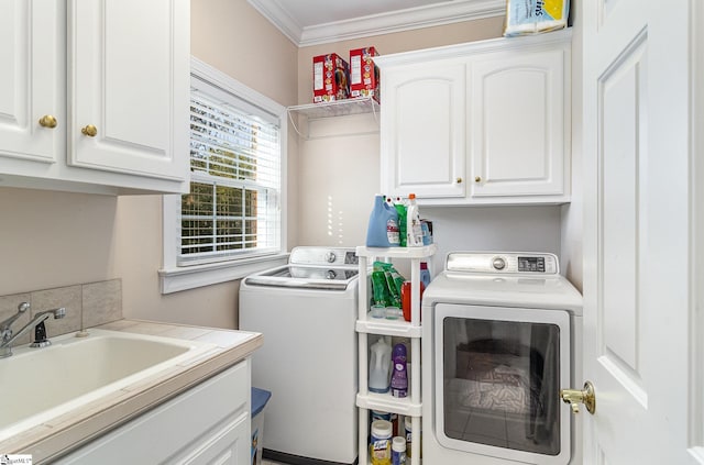 clothes washing area with crown molding, independent washer and dryer, cabinet space, and a sink