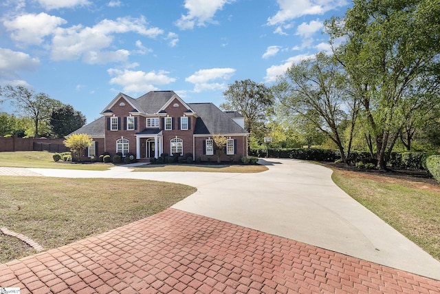 colonial-style house featuring brick siding, curved driveway, and a front lawn