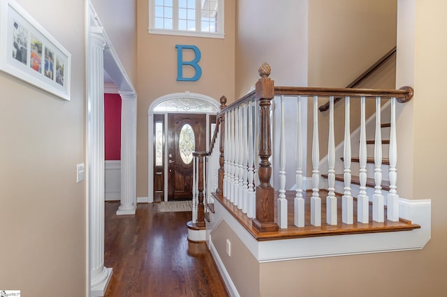 foyer entrance featuring ornate columns, wood finished floors, a high ceiling, and plenty of natural light