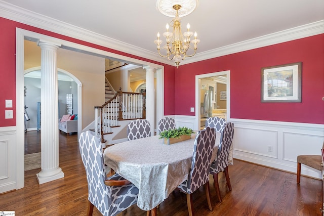 dining area featuring dark wood-type flooring, arched walkways, ornamental molding, and wainscoting