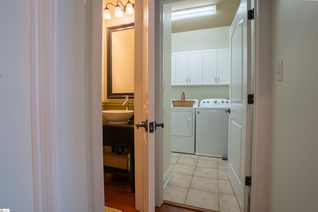 clothes washing area with washer and dryer, light tile patterned floors, a sink, and cabinet space