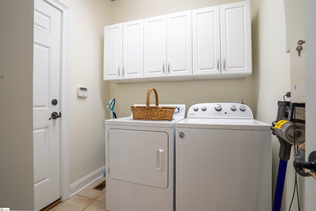 clothes washing area with light tile patterned floors, washer and clothes dryer, baseboards, and cabinet space