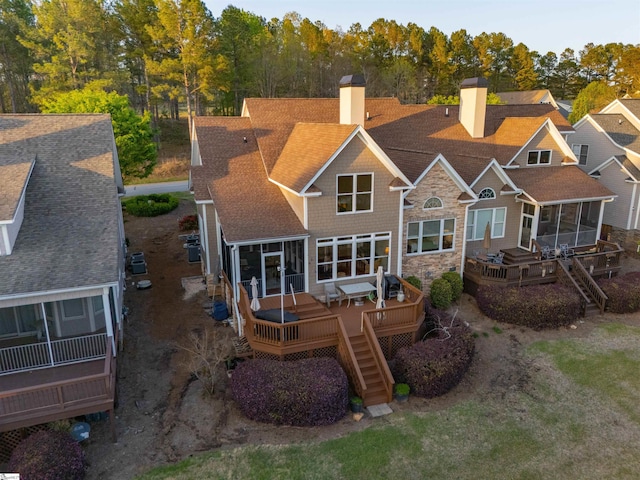 rear view of property with a sunroom, a chimney, a deck, and stairs