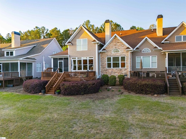 rear view of house with a chimney, a sunroom, a lawn, and stairs