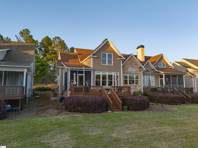 rear view of house with a chimney, stairway, a wooden deck, a yard, and a sunroom