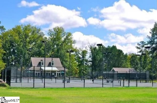 view of property's community featuring a tennis court, fence, and a lawn