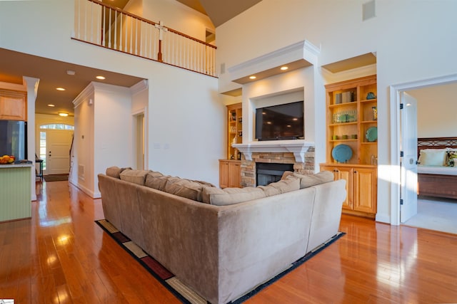 living area featuring a fireplace, a towering ceiling, light wood-type flooring, and visible vents