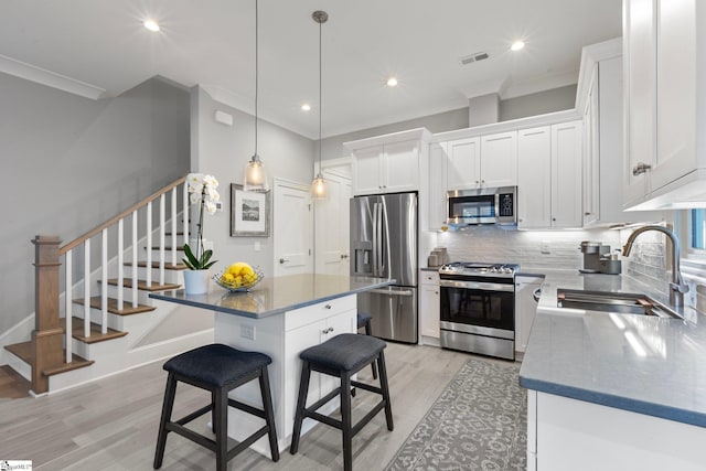 kitchen with a breakfast bar, backsplash, visible vents, stainless steel appliances, and a sink