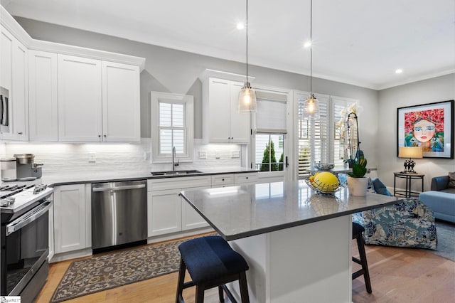 kitchen with a breakfast bar, gas stove, backsplash, dishwasher, and a sink