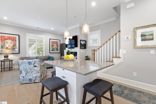 kitchen with a kitchen breakfast bar, baseboards, a center island, light stone countertops, and light wood finished floors