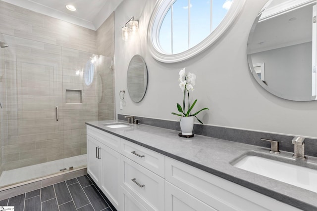 bathroom featuring a stall shower, double vanity, a sink, and recessed lighting