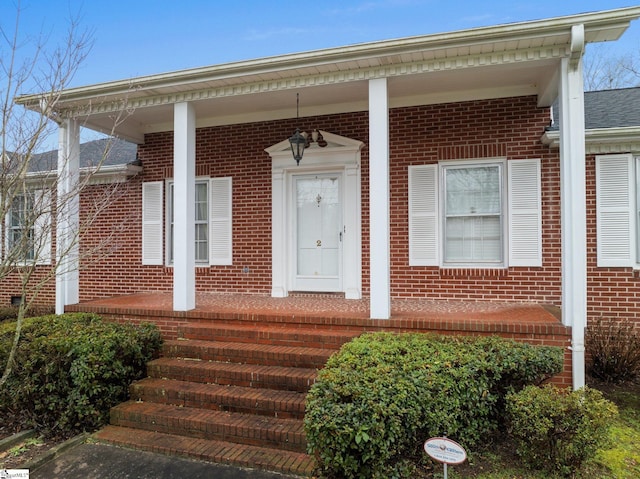 entrance to property with brick siding and covered porch
