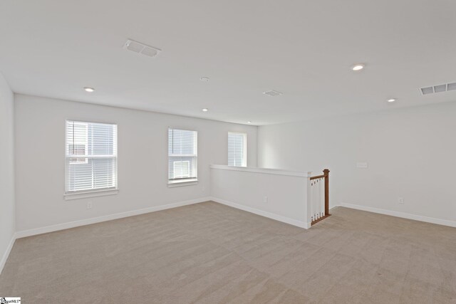 spare room with recessed lighting, visible vents, light colored carpet, and baseboards