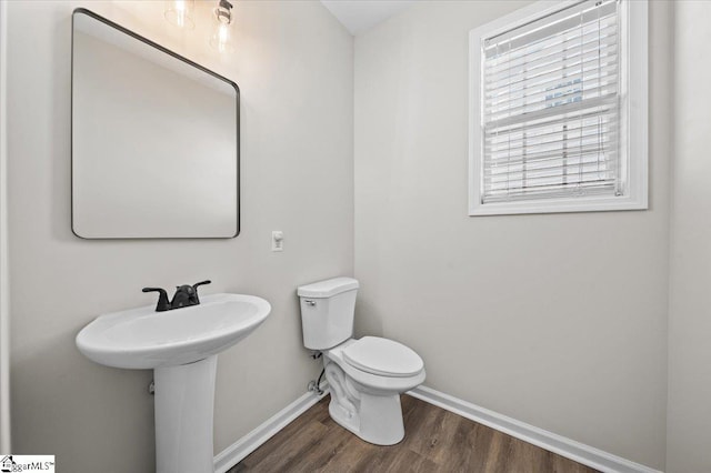 half bathroom with toilet, baseboards, and wood finished floors