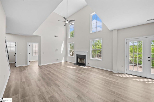 unfurnished living room with visible vents, baseboards, a ceiling fan, light wood finished floors, and a fireplace with flush hearth