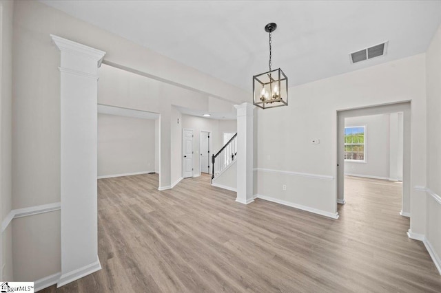 unfurnished dining area featuring visible vents, baseboards, decorative columns, a chandelier, and wood finished floors