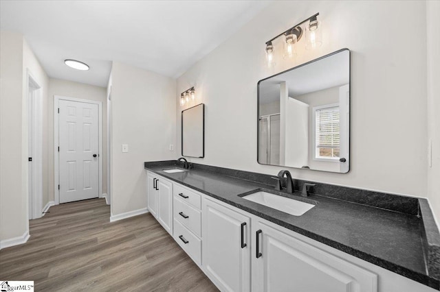 full bathroom featuring a sink, baseboards, double vanity, and wood finished floors