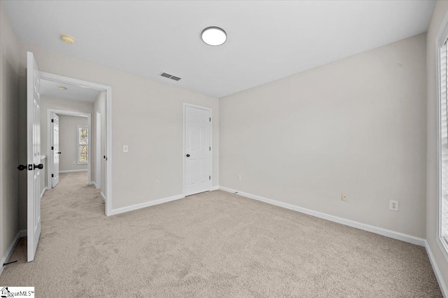 unfurnished bedroom featuring light carpet, baseboards, and visible vents
