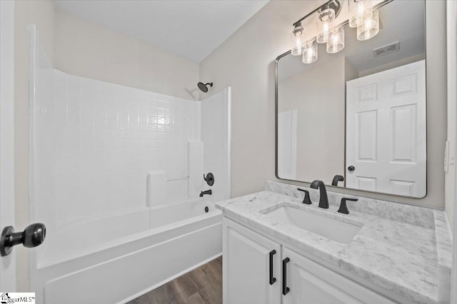 bathroom featuring vanity, visible vents, tub / shower combination, and wood finished floors