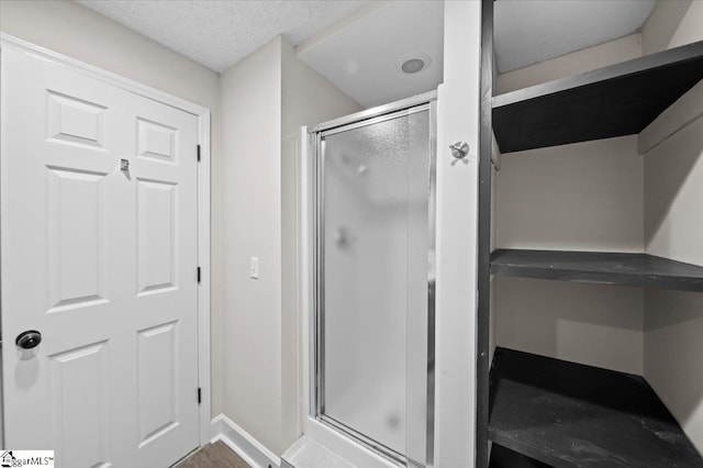 full bathroom featuring a shower stall, baseboards, and a textured ceiling