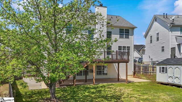 rear view of house featuring an outbuilding, a wooden deck, a storage shed, a patio, and fence