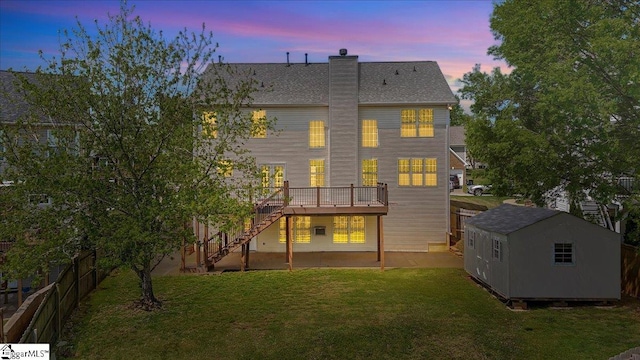 back of property at dusk featuring an outbuilding, stairway, a yard, and a shed