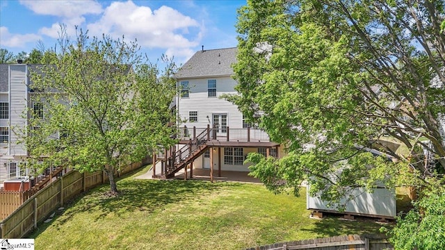 rear view of house with a lawn, a wooden deck, fence, and stairs