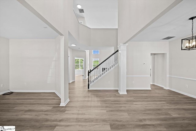 entrance foyer with visible vents, a chandelier, wood finished floors, stairs, and baseboards