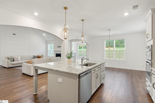 kitchen featuring visible vents, a sink, dark wood-style flooring, appliances with stainless steel finishes, and a center island with sink
