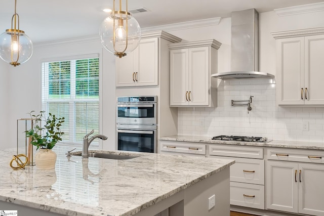 kitchen featuring visible vents, a sink, wall chimney range hood, crown molding, and stainless steel appliances