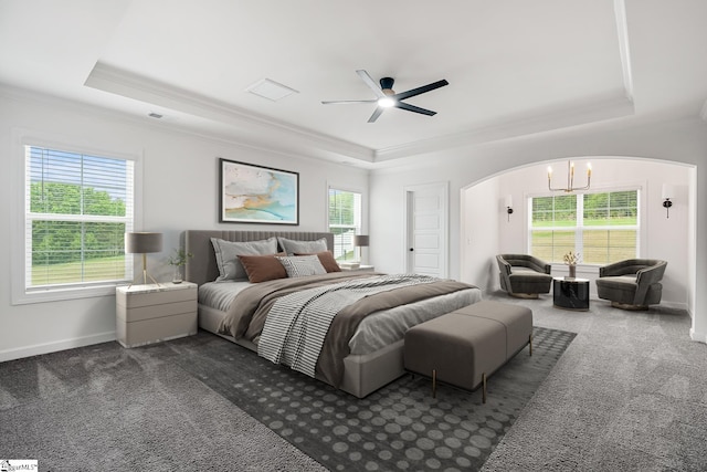 bedroom featuring dark colored carpet, arched walkways, a tray ceiling, and crown molding