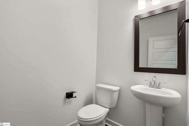 bathroom featuring baseboards, a sink, and toilet