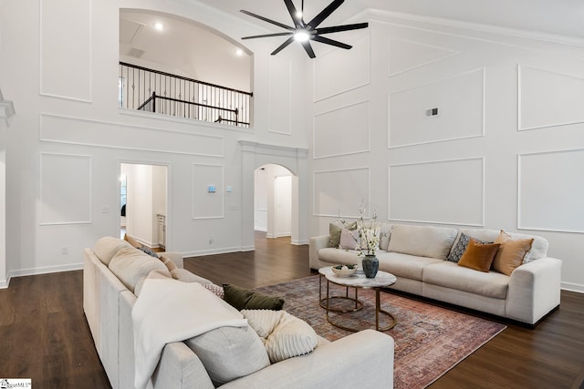 living area featuring visible vents, arched walkways, a high ceiling, dark wood-style flooring, and ceiling fan