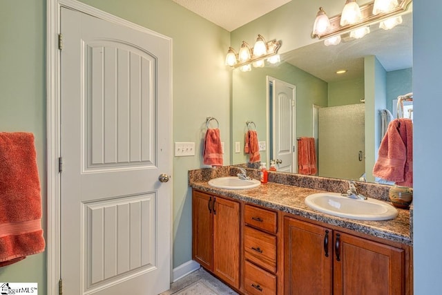 full bathroom with a stall shower, double vanity, and a sink