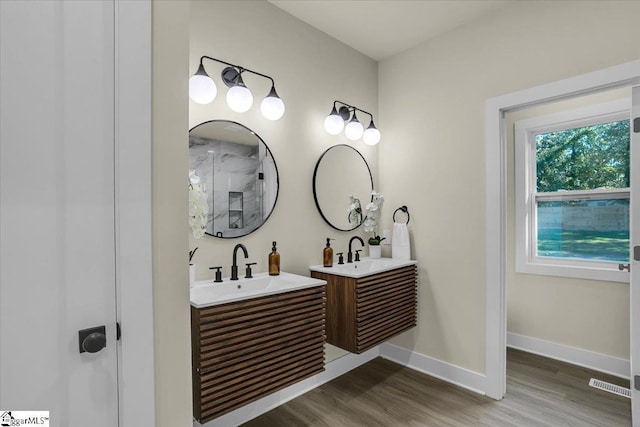 full bath featuring wood finished floors, a sink, two vanities, and visible vents