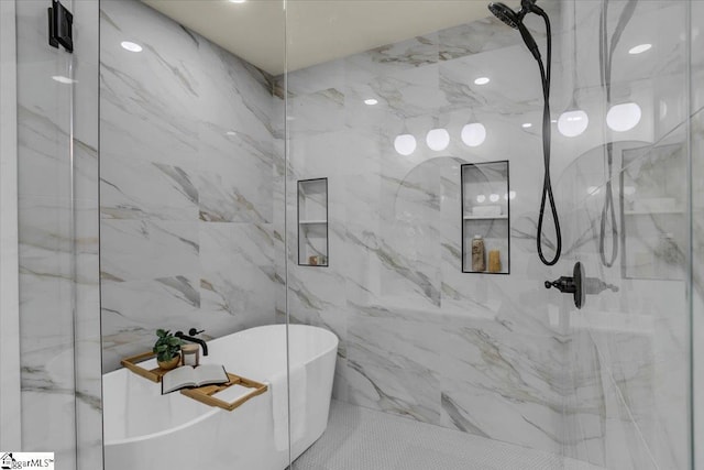 bathroom with a freestanding tub, a marble finish shower, and tile walls