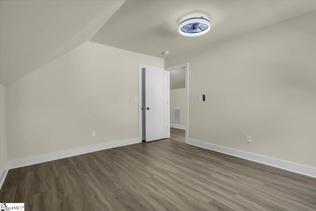 additional living space with visible vents, baseboards, vaulted ceiling, and wood finished floors