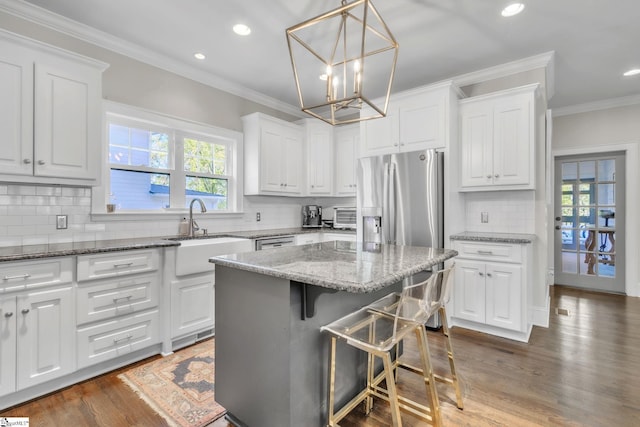 kitchen with white cabinets, tasteful backsplash, a sink, and stainless steel fridge