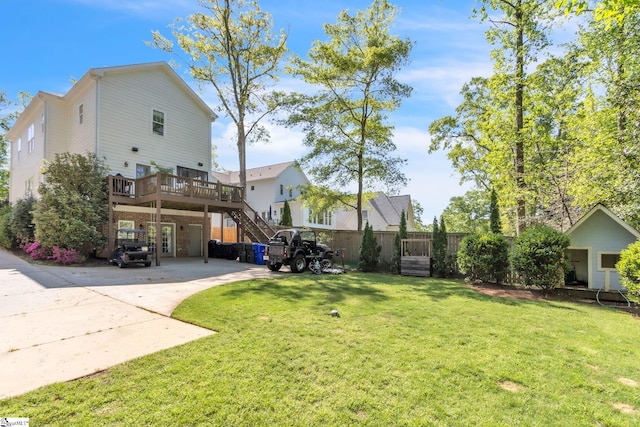 view of yard with concrete driveway, a deck, and stairs